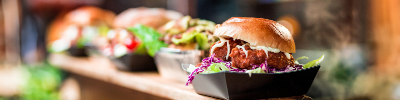 Row of delicious looking burgers lined up at a takeout counter