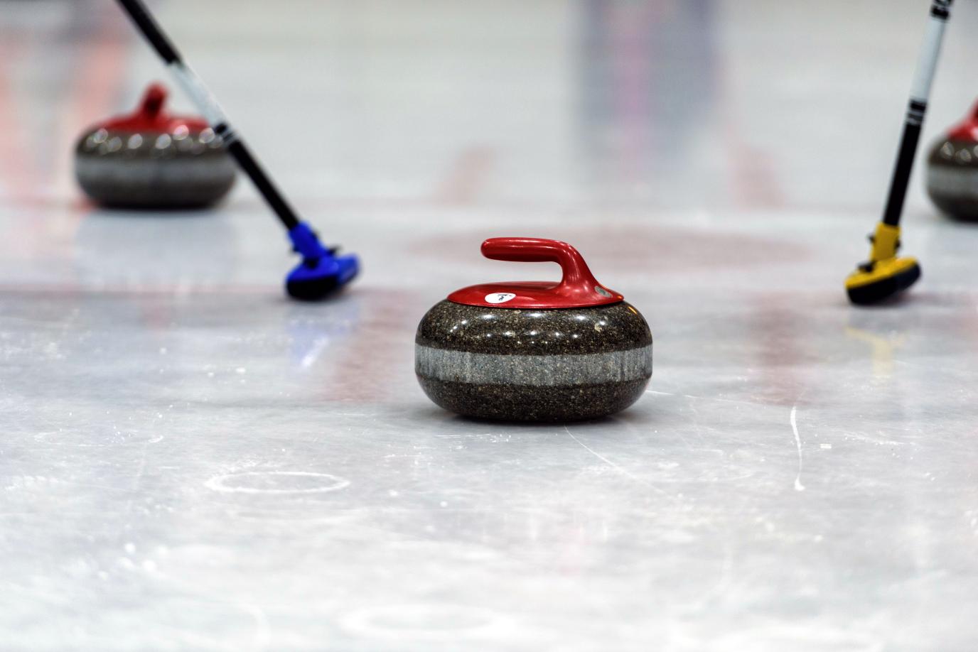 curling rock and brooms on ice