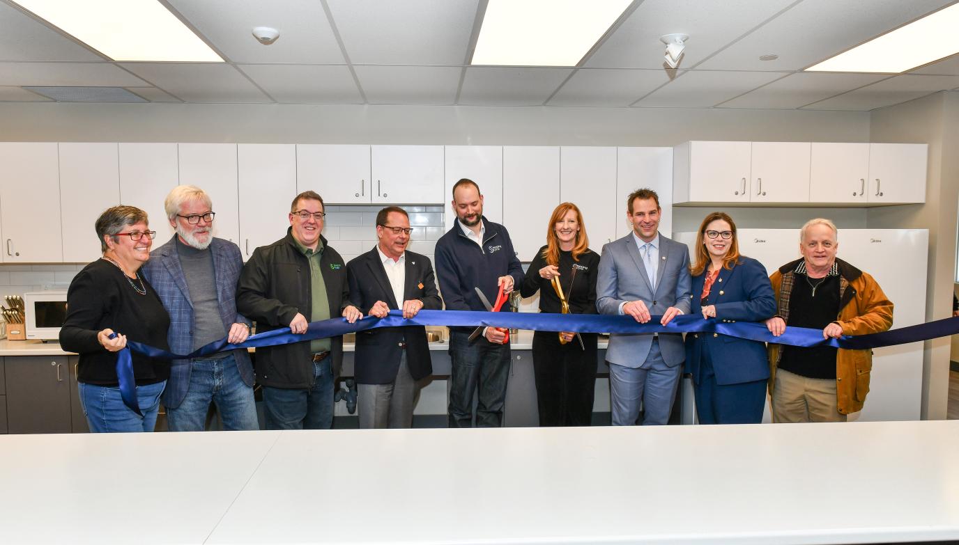 Group of people cutting ribbon in a kitchen. In photo: Linda Busutill, Chair, Joint Social Services and Land Ambulance Committee
